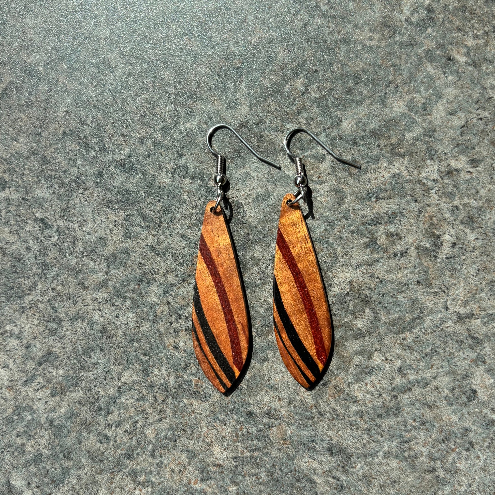 Wooden earrings with black stripes on a gray surface