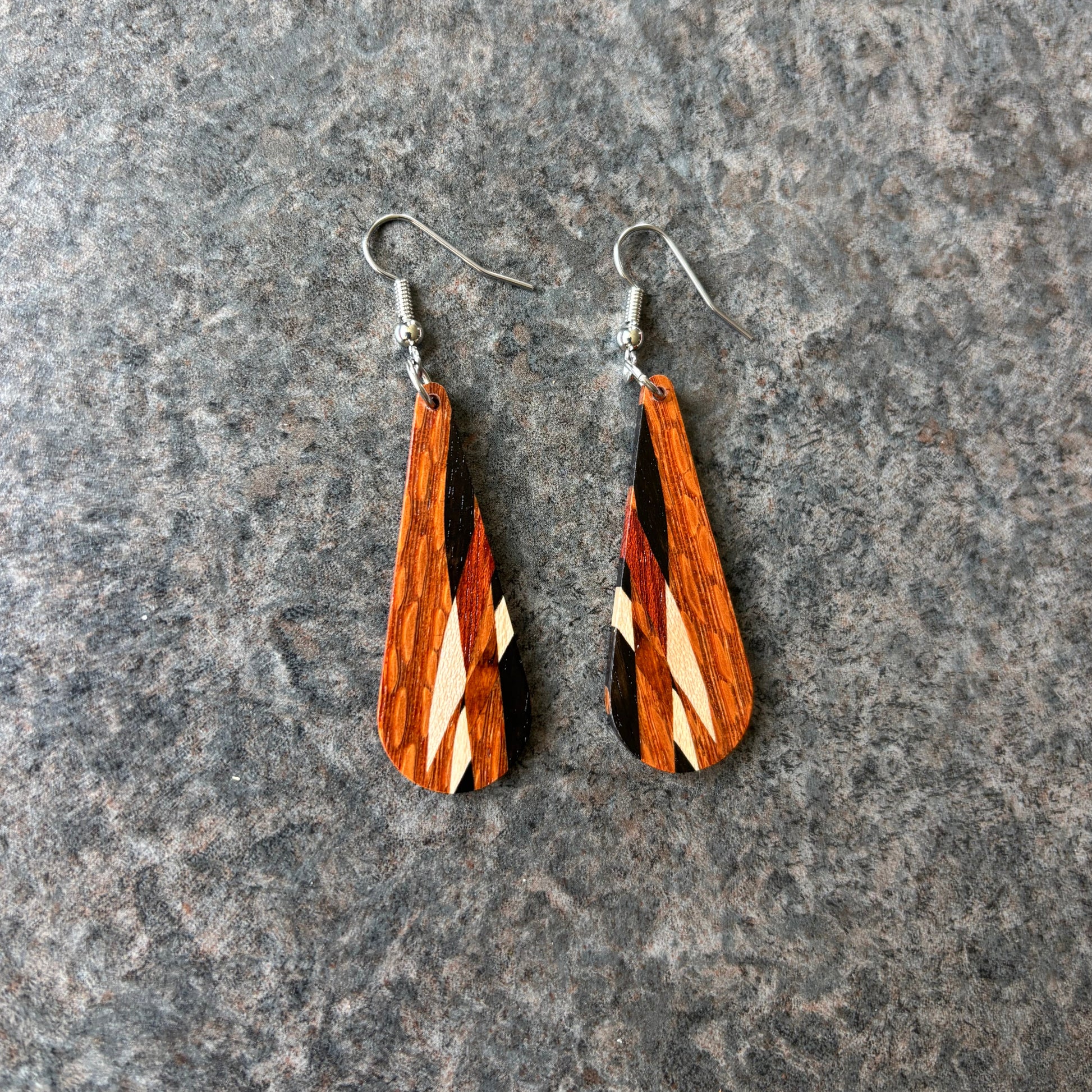 Wooden teardrop earrings on a gray stone surface