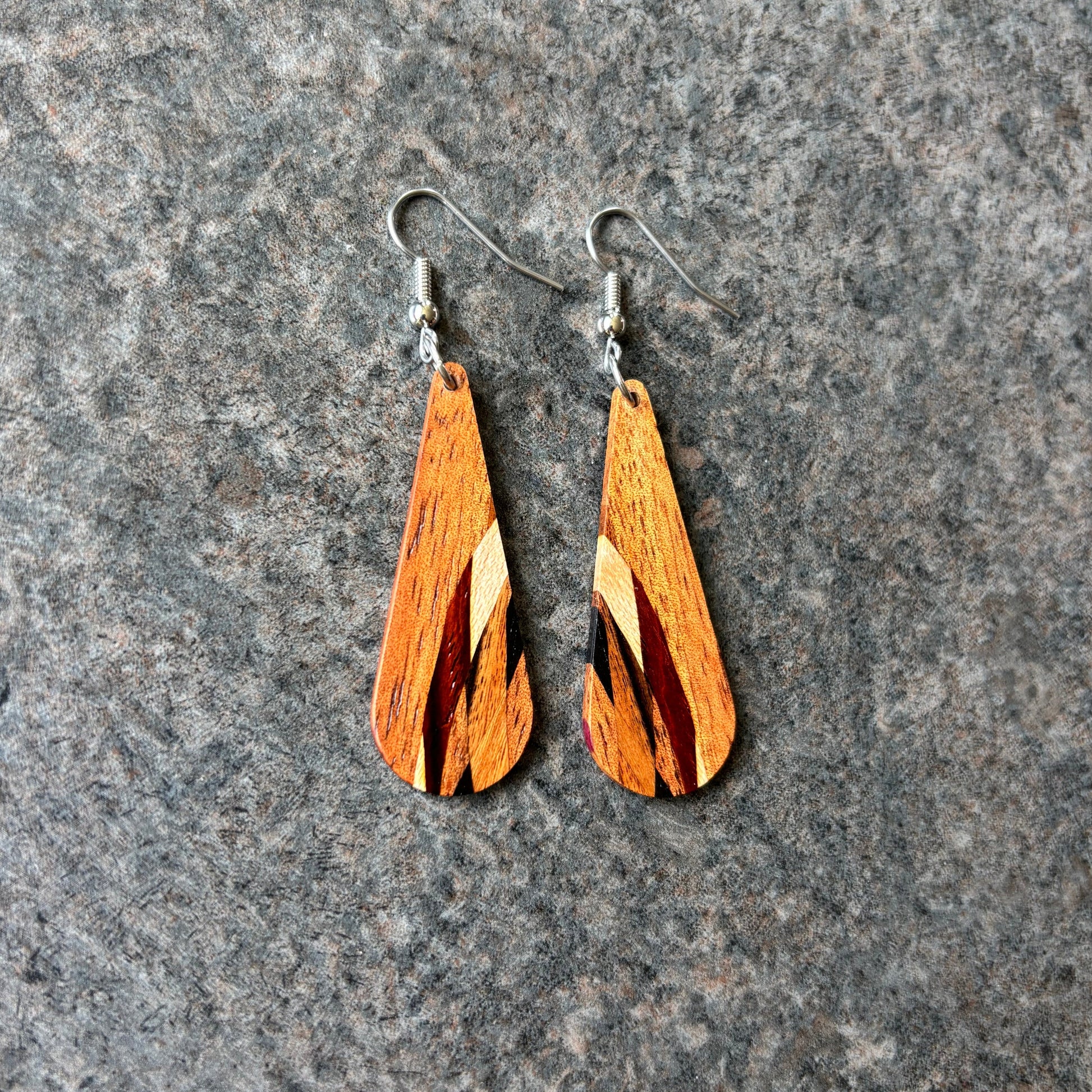 Koa earrings on a gray stone surface