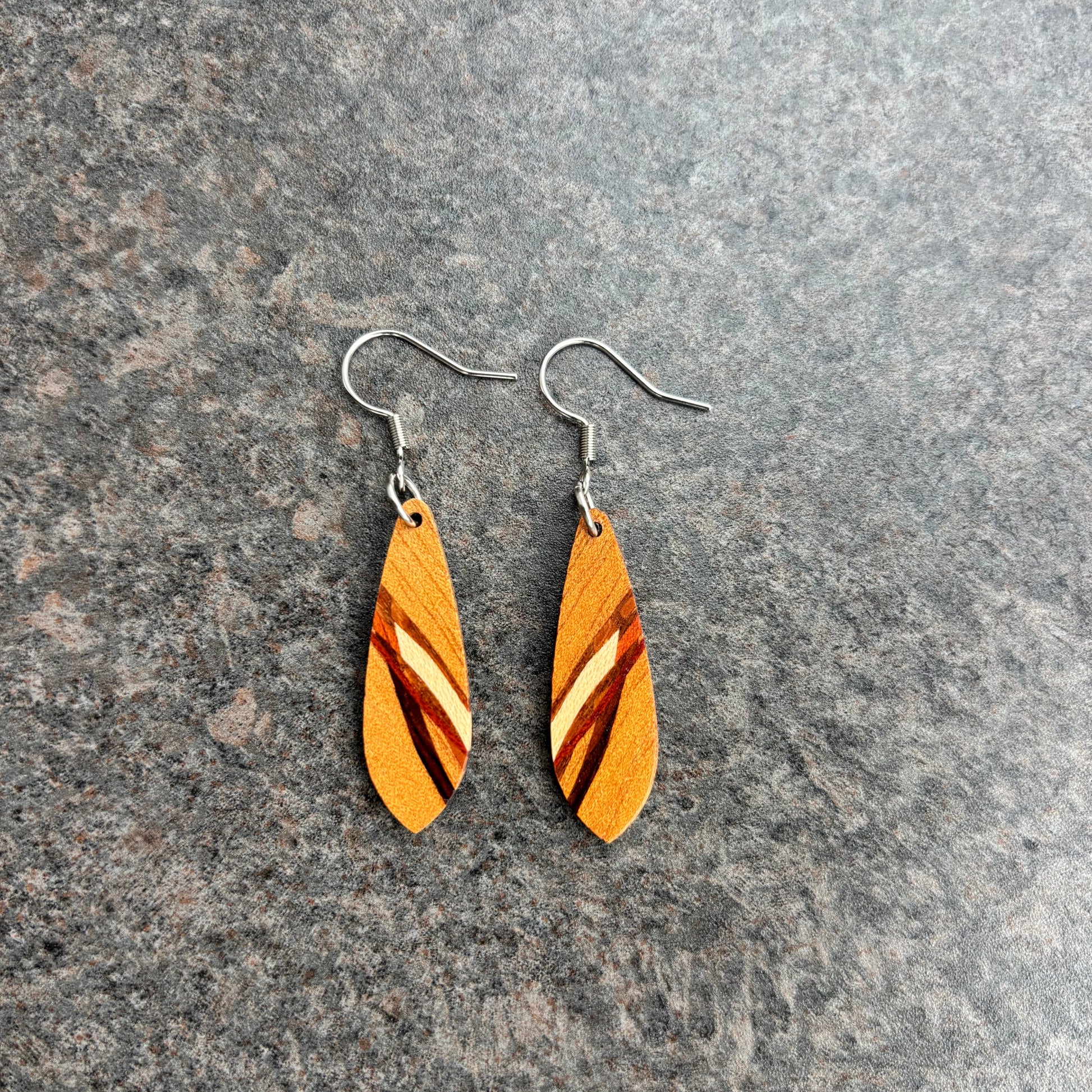 Wooden leaf-shaped earrings on a gray surface