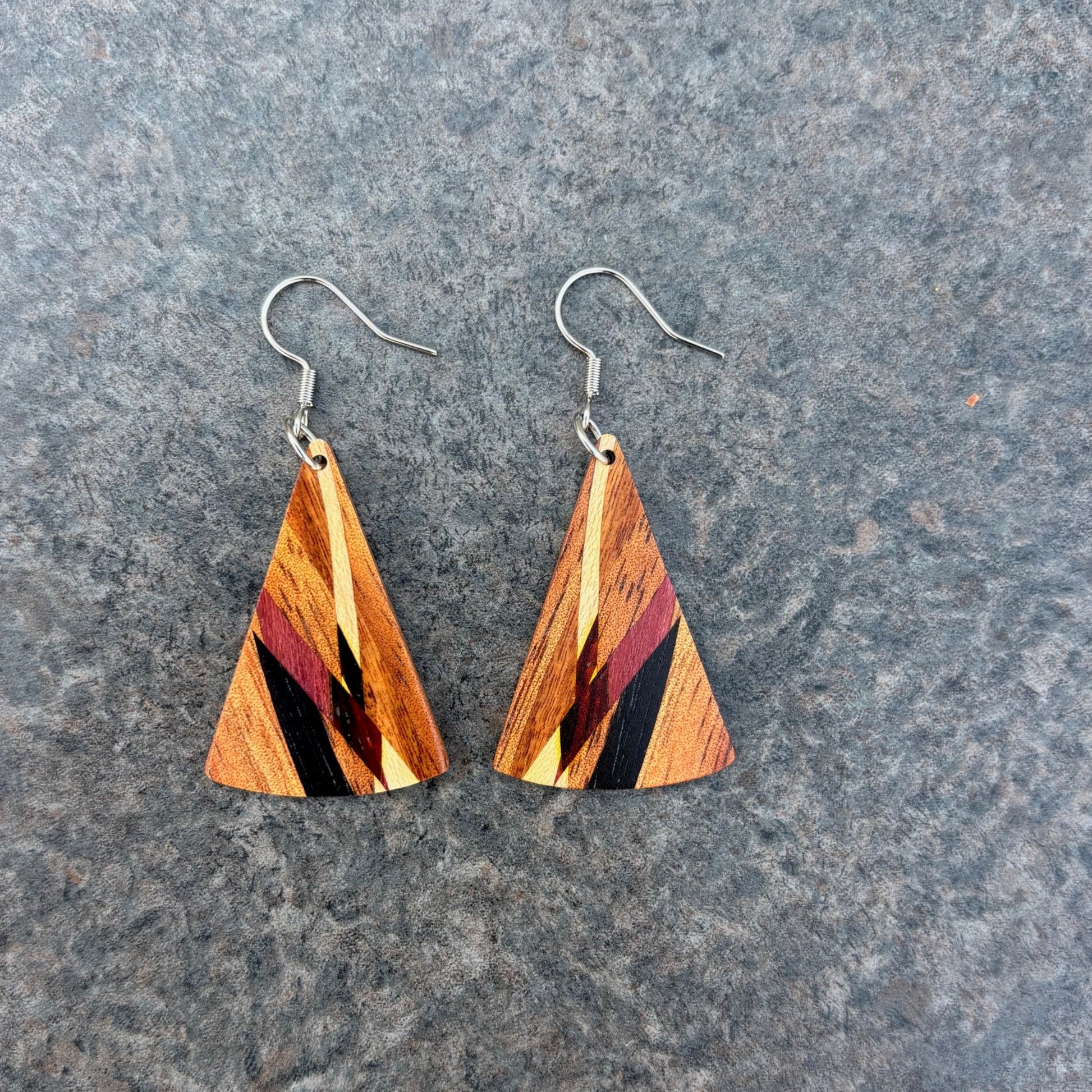 Koa Wood triangle-shaped earrings on a gray surface